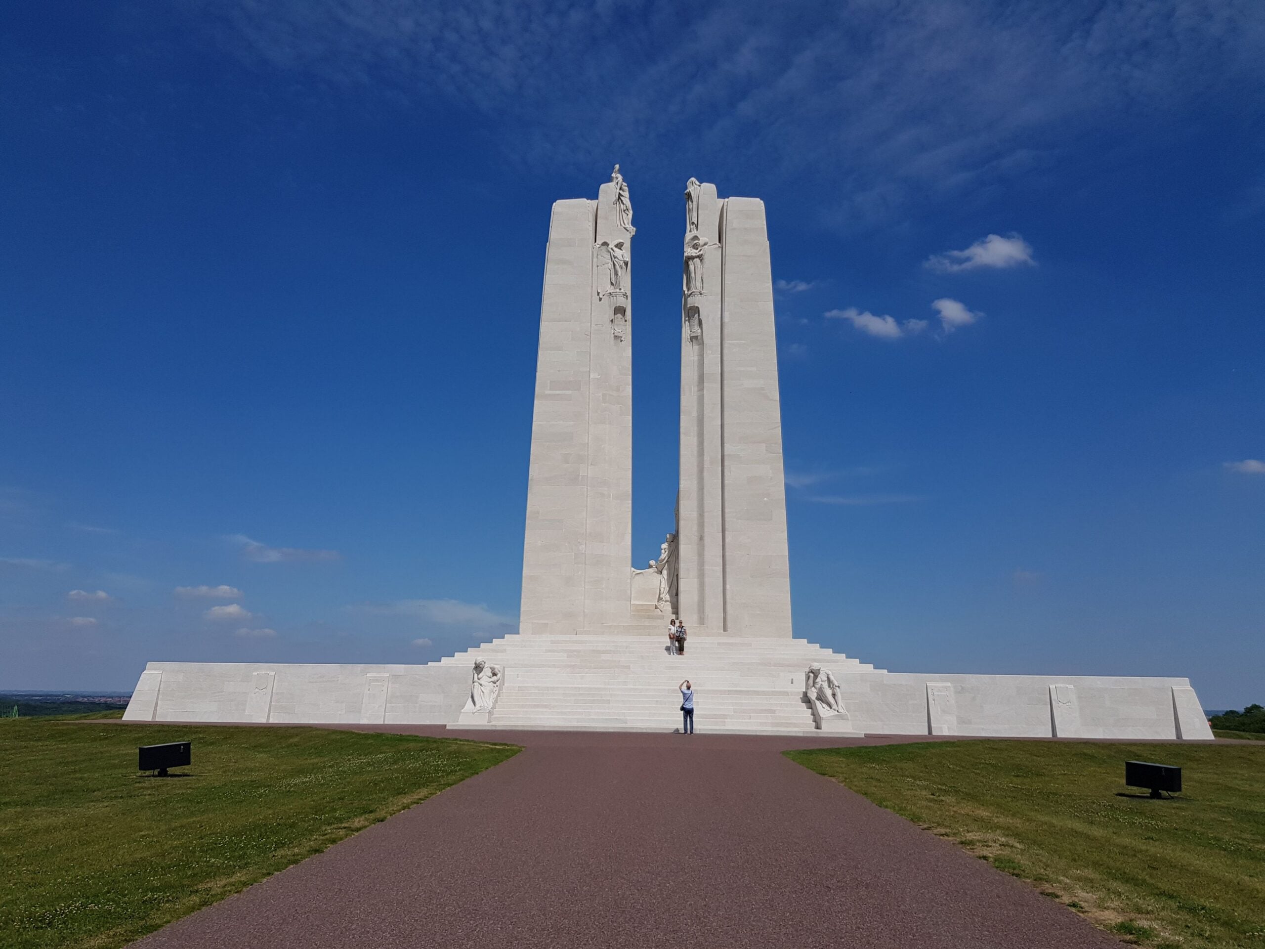 White Vimy Ridge Canadian War Memorial against a blue sky with tourists around