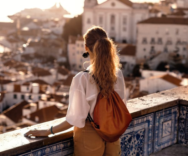 Travel Sunset – Girl Pretty girl looking out over the city wearing a backback and hair up in a pony tail