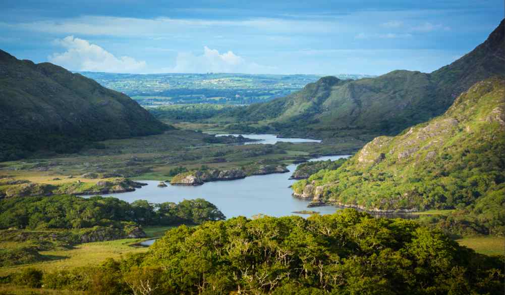 Blue skies over rolling hills of ireland and a lake in the middle - ring of kerry