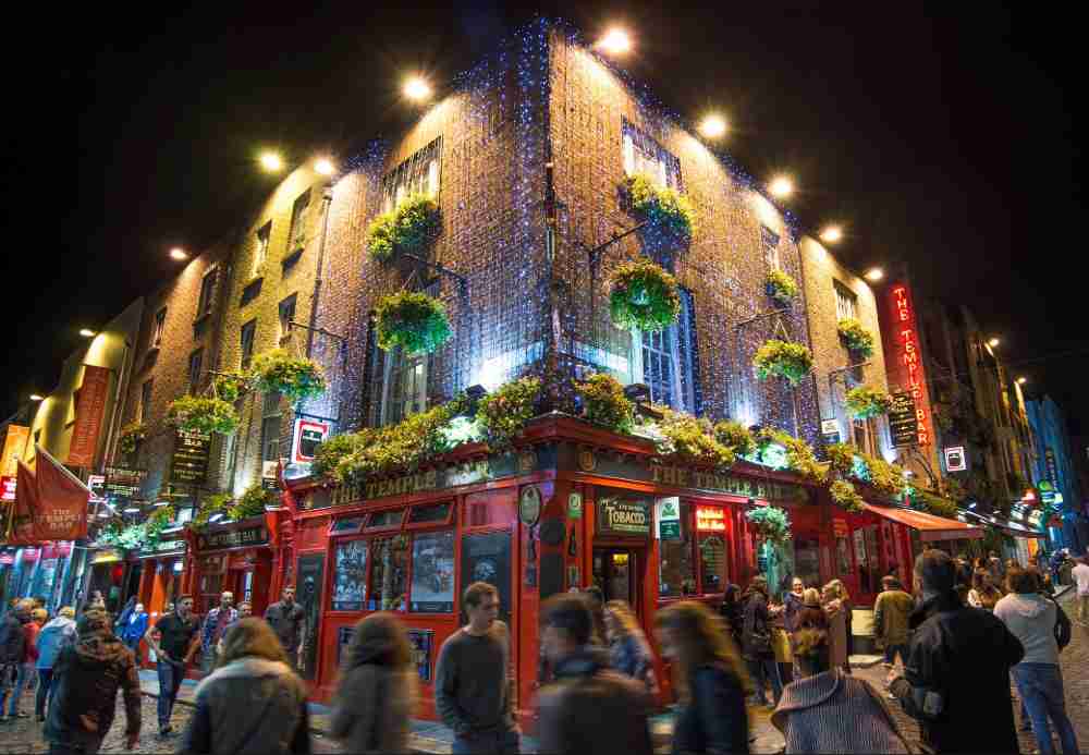 Picture of Temple Bar illuminated at night with people in the foreground having a great time
